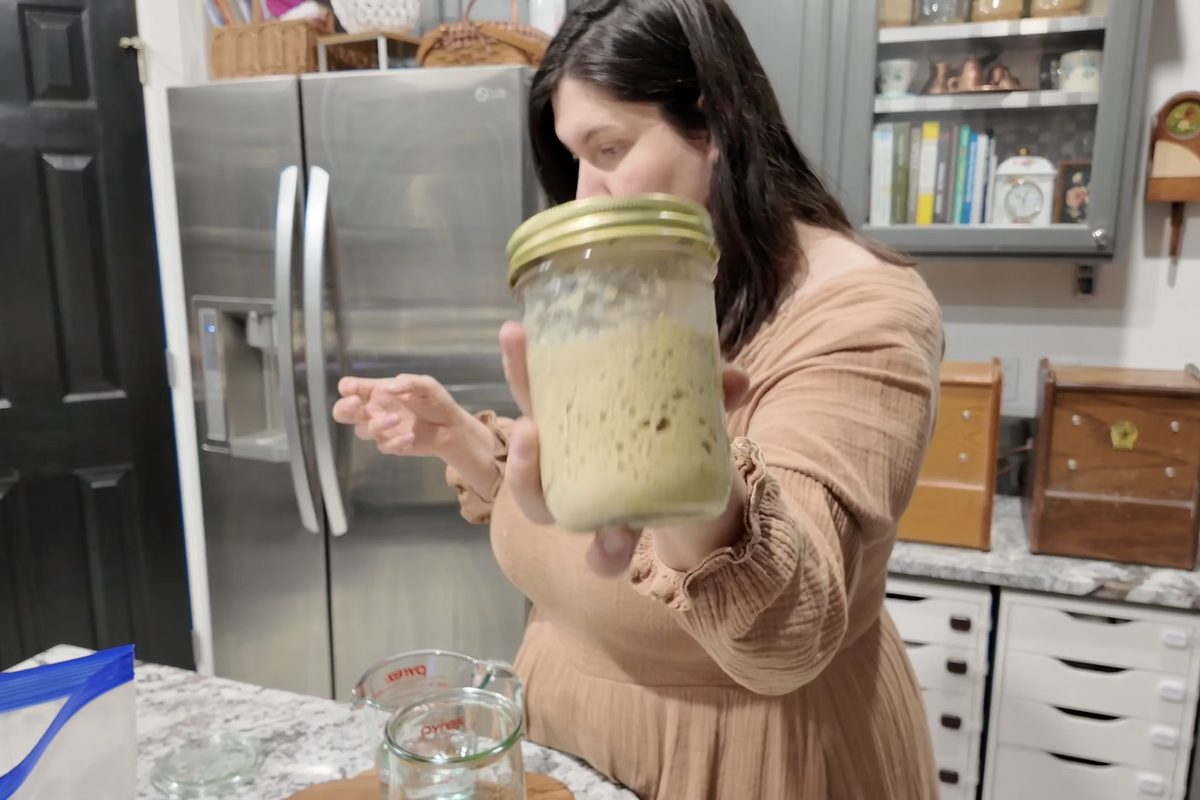 Module 8, Sourdough Starter Prep: holding up a jar of bubbly sourdough starter